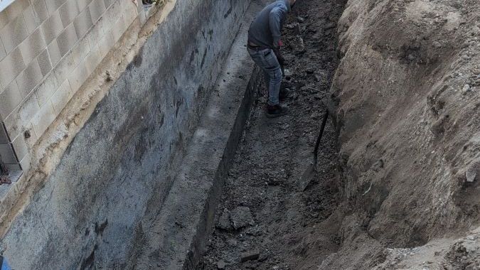 Handarbeit im Detail: Fachgerechte Vorbereitung der freigelegten Kellerwand durch unseren Mitarbeiter.