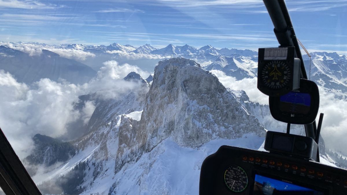 Die Sicht aus dem Helikopter Kockpit auf das frisch verschneite Stockhorn mit Sicht auf die Berner Alpen.