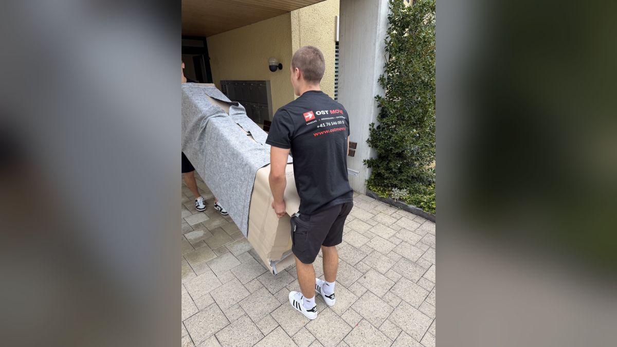 Unsere Umzugshelfer transportieren ein Sofa mit Schutzdecken und Karton. Der sorgfältige Möbelschutz gehört zu unserem professionellen Umzugsservice.