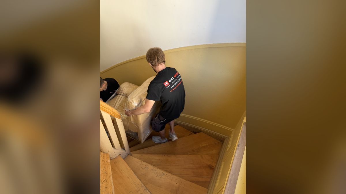 Das OSTMOVE-Team transportiert ein geschütztes Sofa durch ein enges Treppenhaus. Auch sperrige Möbel werden mit besonderer Sorgfalt getragen.